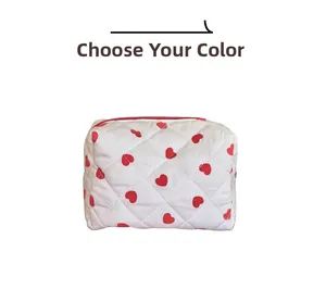 Detail of red heart print on white quilted cosmetic bag with red metal zipper