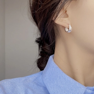 Close-up of S925 sterling silver hoop earrings with vertical ridges on a female model