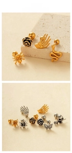 Close-up of gothic style earrings with rose, snake, and skull designs in gold and silver