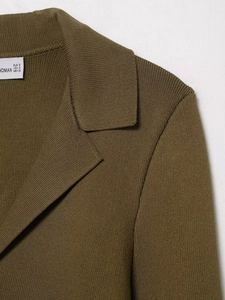 Détail de l'épaule et du col d'un blazer en maille vert olive avec étiquette de taille
