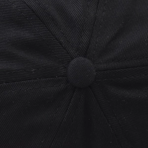 Détail macro de la couronne de casquette en sergé noir avec coutures et bouton supérieur