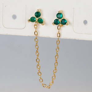 Macro detail of gold-plated flower stud earrings with green zircon and tassel chain link