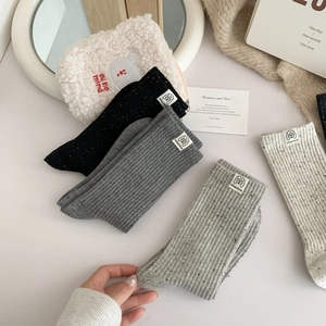 Detail of speckled knit crew socks in grey and cream with dog-themed brand labels