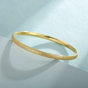 Detail of gold titanium steel bangle showing matte sandblasted texture and mirror finish