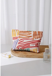 Floral corduroy makeup bag detail with colorful abstract lines on wooden tray
