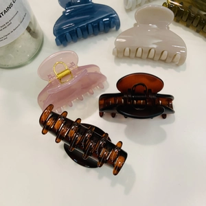 Assorted heart-shaped shark hair clips in tortoiseshell, navy blue, and beige resin