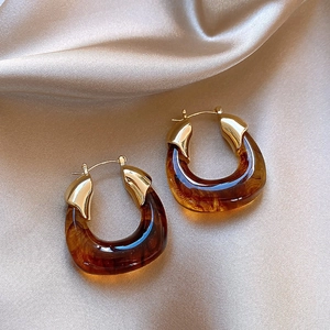Vintage tortoiseshell resin earrings with gold metal accents on silk background