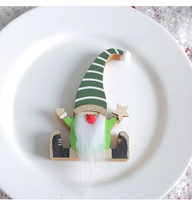 Close-up of wooden Christmas gnome with striped hat holding a star on a snowy plate