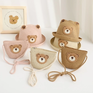 Detail view of woven straw sun hat and matching crossbody bag with cute bear embroidery