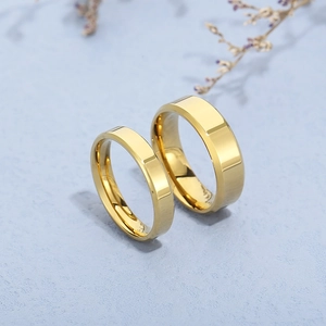 Polished gold stainless steel rings with beveled edges on blue textured background