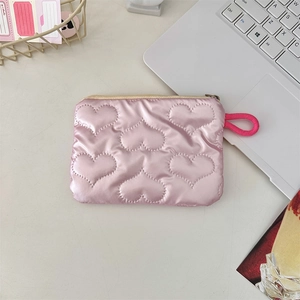 Detail of pink quilted coin purse featuring heart stitching and a side wristlet strap
