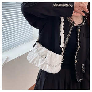 Close-up of white cloud-textured shoulder bag with silver floral chain and fabric label
