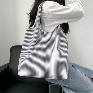 Detail view of casual canvas tote bag with grey vertical stripes on a model