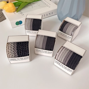 Five boxes of high-elasticity hair bands in grey and black tones on a white table