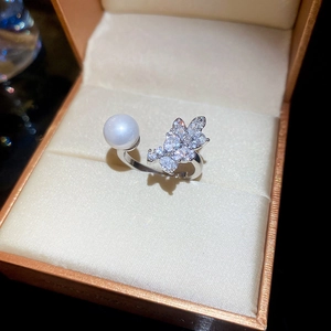 Detailed view of silver open ring with lustrous pearl and sparkling leaf zircon design