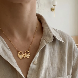 Collier doré avec pendentif cœur deux filles se tenant la main sur un modèle féminin