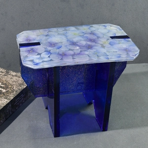 Macro shot of resin DIY stool mold with embedded purple petals and glittery blue base