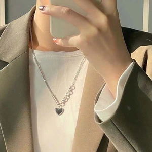 Detail of silver heart pendant necklace with black enamel inlay on a female model