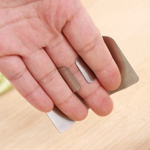 Stainless steel finger guard for cutting vegetables shown on a wooden countertop