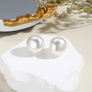 Macro shot of large round white pearl earrings on a natural stone base with vintage frame