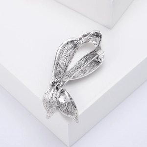 Detailed view of silver leaf-shaped metal brooch with rhinestones on a white background