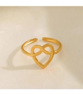 Dettaglio dell'anello dorato a forma di cuore su sfondo di seta beige morbida