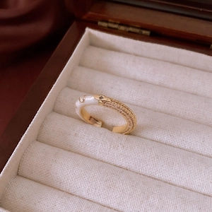 Detail of gold-plated ring with white enamel, cubic zirconia, and floral motifs