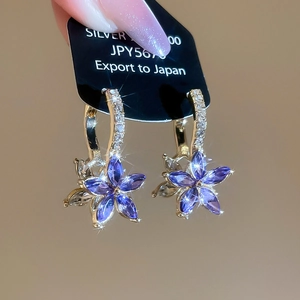 Detailed shot of gold floral earrings with purple zircons and sparkling star effects