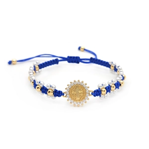 Macro view of blue braided rope bracelet with gold Jesus medal and pavé crystals