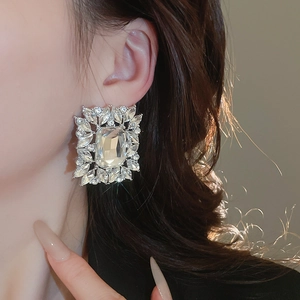 Close-up of elegant silver zircon earrings with emerald-cut crystals on model