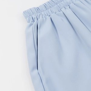 Detail view of light blue shorts with elastic waistband and functional side pockets