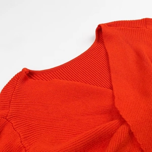 Dettaglio maglione a coste rosse con sexy scollo a V e design con nodo intrecciato