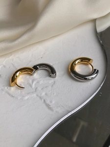 Detailed macro view of two-tone gold and silver splice thick huggie hoop earrings