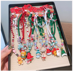 Close-up of Christmas beaded necklaces with Santa and gingerbread man charms in a tray
