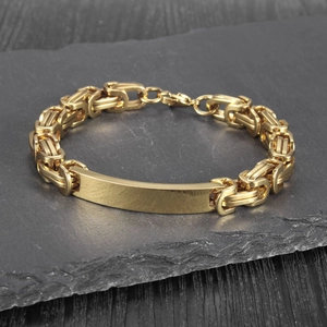 Close-up of golden Byzantine chain bracelet with a polished rectangular metal plate on stone