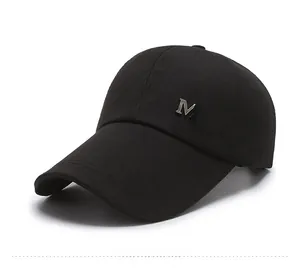 Detail of a black cotton baseball cap featuring a silver metal M logo on the side