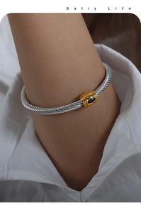 Detail of twisted cable gold and silver bangle with marquise cut blue zircon on wrist