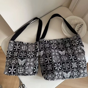 Detailed embroidery texture on black canvas tote bag showing two sizes set