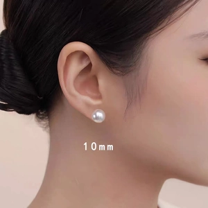 Close-up of 10mm white pearl stud earrings worn by a model for size perspective