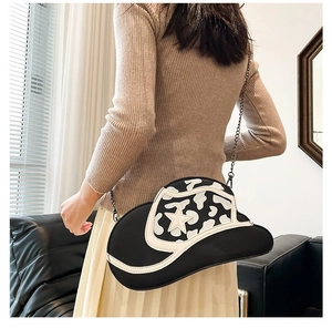 Detail of cow-print cowboy hat shaped crossbody bag with star pattern and chain strap
