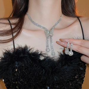 Detailed close-up of luxurious silver bow necklace and tassel earrings with rhinestones