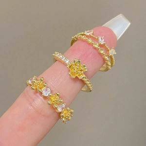 Close-up of gold-plated rings with floral motifs and paved diamonds set of three