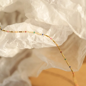 Detail of 18K gold-plated rainbow bead necklace on artistic white background
