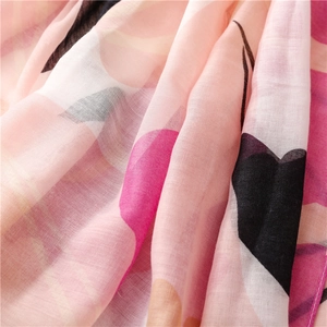 Close-up of lightweight cotton linen scarf showing pink floral patterns and airy weave texture
