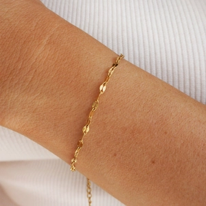 Detail showing an 18K gold plated stainless steel leaf link bracelet worn on the wrist