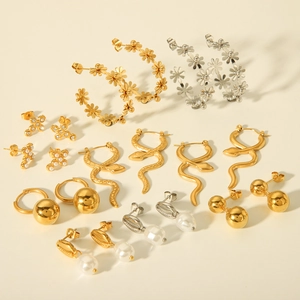 Flat lay of geometric stainless steel earrings in gold and silver with pearl details