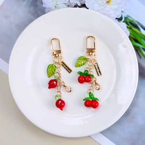 Charming cherry fruit keychain with handmade metal tag and golden lobster clasp on white tray