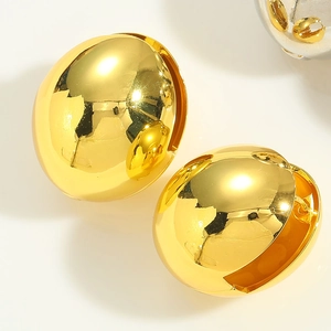 Macro shot of minimalist high-polished gold plated dome earrings on ivory background