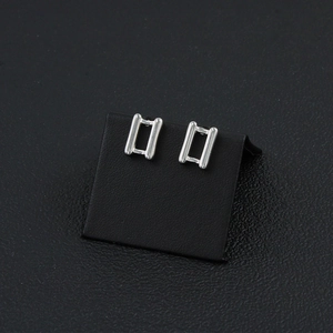 Close-up of silver rectangular stud earrings with a minimalist hollow geometric design
