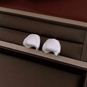Detailed close-up of C-shaped floral earrings with white enamel and silver finish